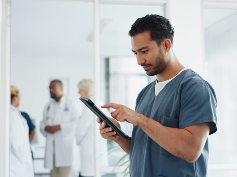 Doctor, tablet and research or planning schedule for healthcare, online medical consultation or search website. Asian man, nurse and reading report or patient analysis on tech device in hospital.